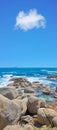 Boulders at a beach shore with majestic ocean across the horizon. Copyspace at sea with blue sky background and rocky