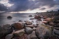 Boulders, forest, shore, evening light, sunset, clouds, blue sky and rainbow on the Baltic Sea. Royalty Free Stock Photo