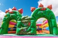 Bouncy castle in the shape of dinosaurs in a children`s playground outdoors