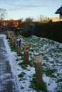 Boundary roadside poles decorated with knitted products against the background of grass under the snow in January. Berlin, Germany