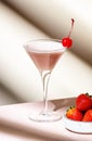 Bounty martini summer cocktail drink with vodka, liqueur, cream, strawberries and ice in glass with red cocktail cherry. Beige Royalty Free Stock Photo