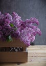 Bouquet of aroma lilacs in a basket on a dark wooden background