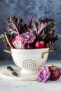 A bouquet arrangement of red and purple vegetables in a vintage colander. Royalty Free Stock Photo