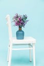 Bouquet of artificial lavender bouquet flowers in glass vase on white chair and blue background. Minimal style interior. Copy Royalty Free Stock Photo