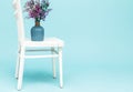 Bouquet of artificial lavender bouquet flowers in glass vase on white chair and blue background. Minimal style interior. Copy Royalty Free Stock Photo