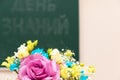 A bouquet of beautiful bright flowers on a school desk on September 1st. The inscription on the school board is the Day of Knowled Royalty Free Stock Photo