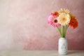 Bouquet of beautiful bright gerbera flowers in vase on marble table against color background. Royalty Free Stock Photo