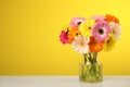 Bouquet of beautiful bright gerbera flowers in vase on table against color background.