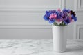 Bouquet of beautiful cornflowers in vase on marble table. Space for text