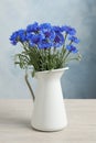 Bouquet of beautiful cornflowers in vase on white wooden table