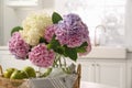 Bouquet of beautiful hydrangea flowers and apples in kitchen, closeup. Interior design element