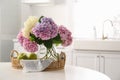 Bouquet of hydrangea flowers and apples on table in kitchen, space for text. Interior design