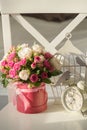 A bouquet of beautiful little roses in a box and a clock in the early morning in the room. Royalty Free Stock Photo