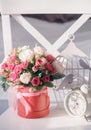 A bouquet of beautiful little roses in a box and a clock in the early morning in the room. Royalty Free Stock Photo