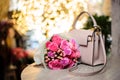 Bouquet of beautiful pink flowers near the stylish handbag on the table Royalty Free Stock Photo