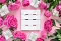 Bouquet of beautiful pink peonies with gift boxes in paper wrapping. Round frame of flowers. White wooden board for text Royalty Free Stock Photo