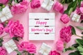 Bouquet of beautiful pink peonies with gift boxes in paper wrapping. Round frame of flowers. White wooden board with text Happy Royalty Free Stock Photo