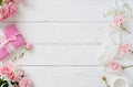 Bouquet of beautiful pink roses and gift in pink packing on white wooden background.Top view.Copy space Royalty Free Stock Photo