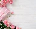 Bouquet of beautiful pink roses and gift in pink packing on white wooden background.Top view.Copy space Royalty Free Stock Photo