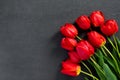 Bouquet of beautiful red tulips on black granite monument with empty space for text