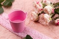 A bouquet of beautiful roses stands in a small bucket on a lace ribbon on a pink craft background with space for text Royalty Free Stock Photo