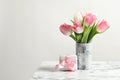 Bouquet of beautiful spring tulips in vase and gift box on marble table against light background. Royalty Free Stock Photo