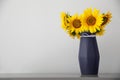Bouquet of beautiful sunflowers in vase on table near light wall. Space for text Royalty Free Stock Photo