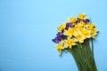 Bouquet of beautiful yellow daffodils and iris flowers on light blue wooden table, top view. Space for text Royalty Free Stock Photo