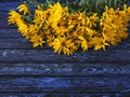 A bouquet of blooming yellow autumn flowers on a background of dark boards with a blue pattern on wood Royalty Free Stock Photo