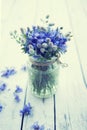 Bouquet of blue cornflowers flowers in a glass jar on an old white wooden board. Floral vintage background with wildflowers Royalty Free Stock Photo