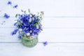 Bouquet of blue cornflowers flowers in a glass vase on an old white wooden board. Floral background with wildflowers Royalty Free Stock Photo