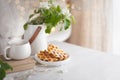 A bouquet of branches of a blossoming apple tree stands in a white vase on the table. Viennese waffles on a plate Royalty Free Stock Photo