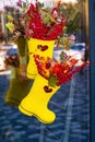 A bouquet of branches with red berries in yellow rubber boots hangs on the store door