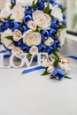 A bouquet of the bride from white and blue roses and wedding rings from gold Royalty Free Stock Photo