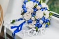 A bouquet of the bride from white and blue roses and wedding rings from gold Royalty Free Stock Photo