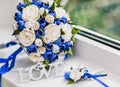 A bouquet of the bride from white and blue roses and wedding rings from gold Royalty Free Stock Photo