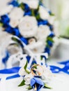 A bouquet of the bride from white and blue roses and wedding rings from gold Royalty Free Stock Photo