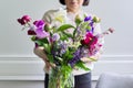 Bouquet of bright flowers of peonies irises lupins in the hands of woman close-up