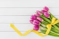 Bouquet of bright pink tulips decorated with yellow ribbon on white wooden background Royalty Free Stock Photo