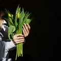 Bouquet of bright yellow tulips in female hands on black isolated background. Close-up, copy space. Concept of greeting Royalty Free Stock Photo