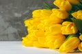 Bouquet of bright yellow tulips lying on white wooden surface on gray background. Copy space Royalty Free Stock Photo