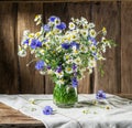 Bouquet of chamomiles and cornflowers in the vase.