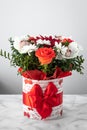 Bouquet of colorful flowers in a box with red ribbon bow on gray background. Gift, greeting card Royalty Free Stock Photo