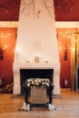 Bouquet of colorful flowers in front of a fireplace adorned with decorative chandelier lights.