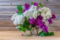 Bouquet of colorful lilac flowers in a glass vase on a wooden background