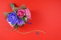 A bouquet of colorful paper flowers and a small blue heart on a red background as a backdrop for a postcard, invitation letter and Royalty Free Stock Photo