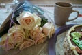 Bouquet of cream roses, Kiev cake and a cup on the table.