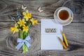 Bouquet of Daffodils and Muscari on wooden table with card, butterflies and cup of tea. Royalty Free Stock Photo