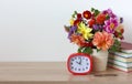 Bouquet of dahlias, an alarm clock and textbooks on the table Royalty Free Stock Photo