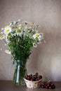 Bouquet of daisies and basket of cherries